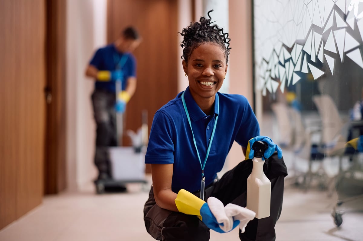 Professional African American cleaner wiping glass walls